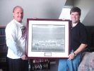 George South and DIck Bourne hold a photo of the greensboro Coliseum that originally hung in Jim Crockett's office.
